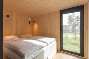 Cama en habitación con ventana en Hello Zeeland - Zeeuwse Liefde Tiny House 7 en Westkapelle