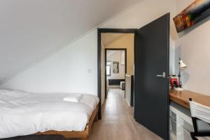 a bedroom with a white bed and a black door at Hello Zeeland - Spaanse Galeien 35 in Retranchement