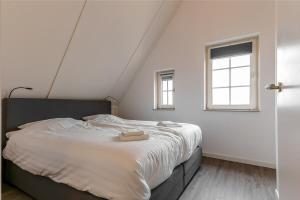 a white bedroom with a large bed with two windows at Hello Zeeland - vakantiewoning Knuitershoek 66 