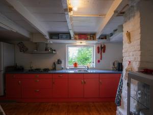 eine rote Küche mit einem Waschbecken und einem Fenster in der Unterkunft Hello Zeeland - Vakantiewoning 't Schrijvershuisje in Hengstdijk