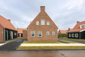 una casa de ladrillo con ventanas blancas en una calle en Hello Zeeland - vakantiewoning Knuitershoek 102 