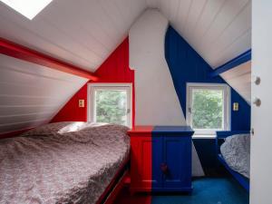ein rotes und blaues Schlafzimmer mit einem Bett und zwei Fenstern in der Unterkunft Hello Zeeland - Vakantiewoning 't Schrijvershuisje in Hengstdijk
