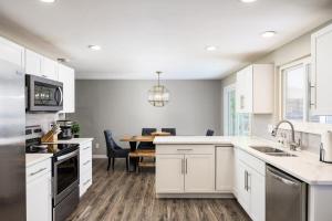 a kitchen with white cabinets and a dining table at Denver Family Retreat 4BR 3 BA - Large Backyard in Arvada