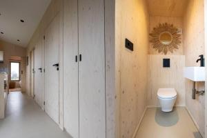 bagno con armadi bianchi e servizi igienici di Hello Zeeland - Tiny House Zeeuwse Liefde 6 a Westkapelle