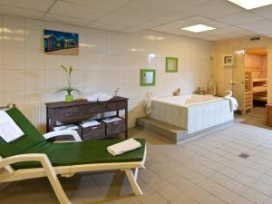 a large bathroom with a tub and a green chair at ACHAT Hotel Bochum Dortmund in Bochum