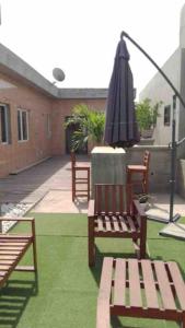 eine Terrasse mit einem Sonnenschirm, 2 Bänken und einem Sonnenschirm in der Unterkunft TANIA GUESTHOUSE in Lomé