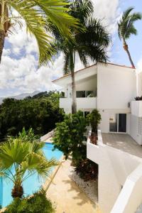a white house with palm trees and a swimming pool at Casa Jobo - Mountain & Sea Panoramic view- 3Bedrooms in San Felipe de Puerto Plata