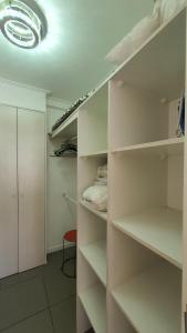 a walk in closet with white shelves and a light at Edificio One in Iquique