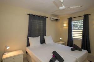 een slaapkamer met een wit bed en zwarte gordijnen bij Caracara M4 Relax & Dive Resort Bonaire Village in Kralendijk