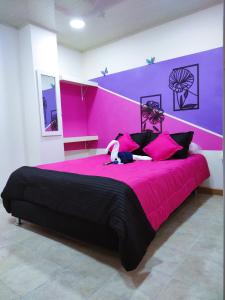 a bedroom with a pink bed with a stuffed animal on it at Hostal Carvajal in Bogotá