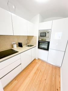 a kitchen with white cabinets and a wooden floor at Bombarda 15 Evora in Évora