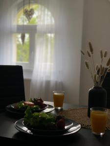 a table with two plates of food and two glasses of orange juice at Apartamenty Astor - Słoneczny in Szczawno-Zdrój