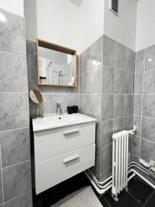 ein Badezimmer mit einem weißen Waschbecken und einem Spiegel in der Unterkunft 2p : Vue sur les toits de Paris in Les Lilas