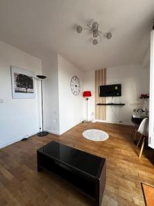 uma sala de estar com uma mesa de centro e um relógio na parede em 2p : Vue sur les toits de Paris em Les Lilas