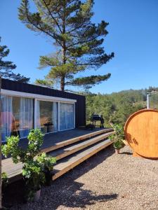 a tiny house with a large deck and a tree at Tiny house OMA in Laguna Verde