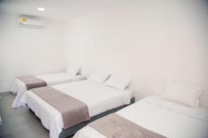 three beds in a room with white walls at CASA HOTEL SANTA INES in Mompós