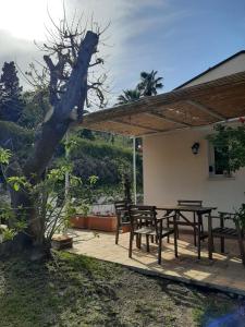 eine Terrasse mit einem Tisch, Stühlen und einem Baum in der Unterkunft Appartamento In Villa Al Mare - Baia di Arcile in Brucoli