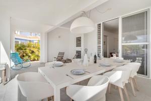 uma sala de jantar branca com uma mesa e cadeiras brancas em Casa Leeward with Pool on the Laguna Marina em Kralendijk