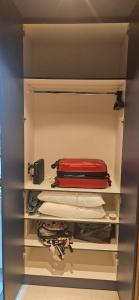 um closet cheio de roupas e uma mala vermelha em Loft aconchegante na melhor localização de BH em Belo Horizonte