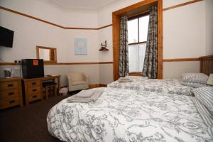 a bedroom with a bed and a desk and a window at Alder Lodge Guest House in Lerwick