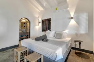 ein weißes Schlafzimmer mit einem Bett und zwei Stühlen in der Unterkunft Costa de la Luz on the water of the Laguna Marina in Kralendijk + 50 Fotos