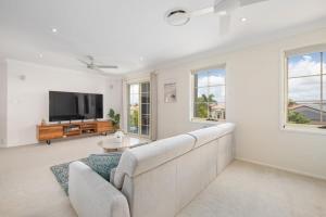 ein Wohnzimmer mit einem Sofa und einem TV in der Unterkunft Pool Sauna Cinema Office Room 4BR Spacious house in Gold Coast