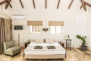 ein weißes Schlafzimmer mit einem Bett und einem Stuhl in der Unterkunft Nirvana Lodge with Private Pool and House Reef in Kralendijk + 38 Fotos