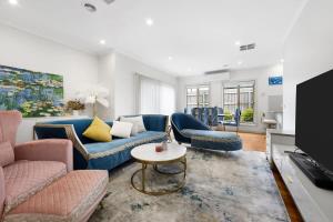 a living room with blue couches and a tv at 3BR Townhouse 7km to Chadstone in Chadstone