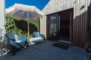 zwei Stühle und ein Regenschirm auf einer Terrasse in der Unterkunft Hello Zeeland - Vakantiehuis Kerkstraat 1A in Domburg