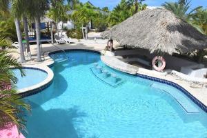 einen Pool in einem Resort mit Strohdach in der Unterkunft Villa de Agua 7 in Waterlands Village in Kralendijk