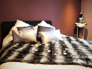 Cama con manta y almohadas blancas y negras en Symbiose hotel, en Charleroi
