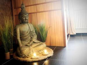 een standbeeld van een Boeddha zittend op een tapijt met kaarsen bij Symbiose hotel in Charleroi