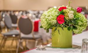 a green vase with red and white flowers on a table at Hotel 116, A Coast Hotel Bellevue in Bellevue
