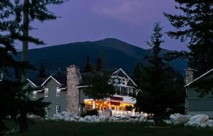 a house with lights on in front of a mountain at Tekarra Lodge in Jasper