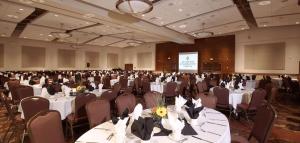 un salón de banquetes con mesas, sillas y una pantalla en Coast Hotel & Convention Centre, en Langley