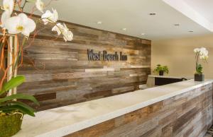 a lobby with a wooden wall with the words west hospitaliman at West Beach Inn, a Coast Hotel in Santa Barbara