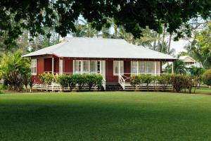 una casa roja con césped delante en Waimea Plantation Cottages, a Coast Resort, en Waimea