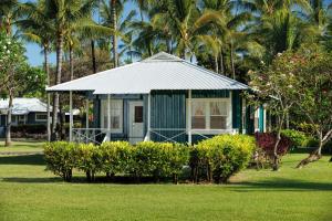 uma pequena casa azul num quintal com palmeiras em Waimea Plantation Cottages, a Coast Resort em Waimea