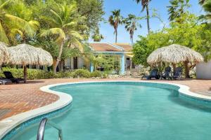 une piscine bordée de palmiers et une maison dans l'établissement Kas Kontentu in Caribbean Court, à Kralendijk