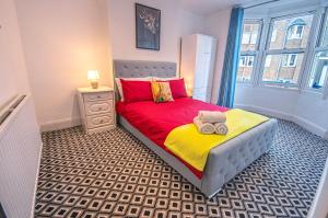 ein kleines Schlafzimmer mit einem Bett mit roter und gelber Bettwäsche in der Unterkunft Central 3-Bedroom Townhouse with Patio in Brighton in Brighton & Hove