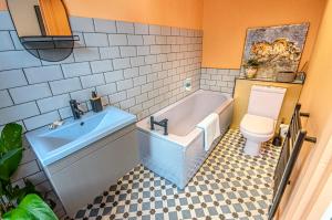 ein Badezimmer mit einer Badewanne, einem WC und einem Waschbecken in der Unterkunft Central 3-Bedroom Townhouse with Patio in Brighton in Brighton & Hove