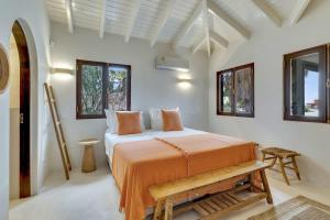 ein Schlafzimmer mit einem Bett mit orangefarbener Bettwäsche und Fenstern in der Unterkunft Coral Laguna in Laguna Marina in Kralendijk + 49 Fotos
