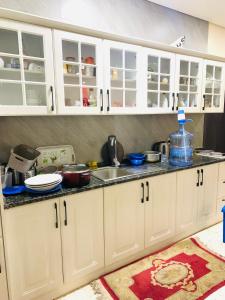 Una cocina con gabinetes blancos y un fregadero. en Arsaad villa apparments, en ‘Ūd al Bayḑāʼ