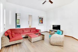 uma sala de estar com um sofá vermelho e duas cadeiras em Villa Kromboon with an amazing sea view em Kralendijk