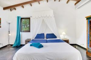 um quarto com uma grande cama branca com almofadas azuis em Villa Kromboon with an amazing sea view em Kralendijk