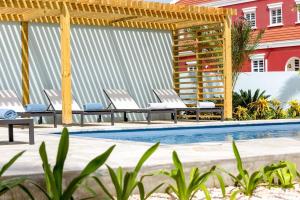 a pool with chairs and a pergola next to a building at Liv Inn Bonaire with Pool and Nice Cooling Winds in Kralendijk