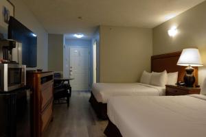 a hotel room with two beds and a desk at Coast Parksville Hotel in Parksville