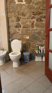 a bathroom with a toilet and a stone wall at Bitro House in Pogradec