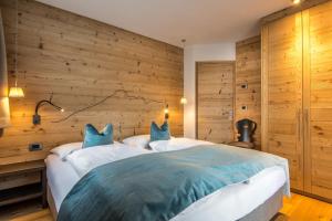 - une chambre avec un grand lit et un mur en bois dans l'établissement Chalet Prades Dolomiti Lodges, à La Villa