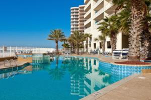 una gran piscina con palmeras y un edificio en Admirals Quarters 1009, en Orange Beach